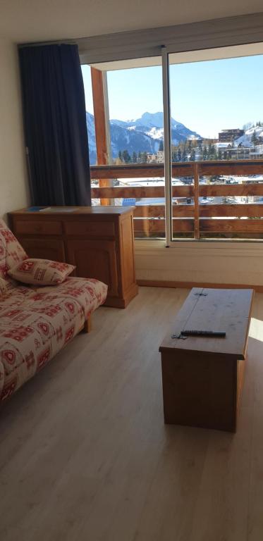 a bedroom with a bed and a table and a large window at appartement au pied des pistes in Orcières