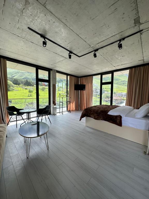 a bedroom with a bed and a table and chairs at Hotel NOA Kazbegi in Stepantsminda