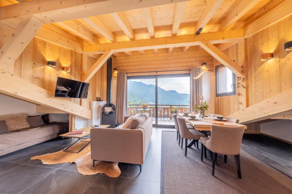 a dining room with a table and chairs and a large window at Appartements Chalet Le Fornay in Morzine
