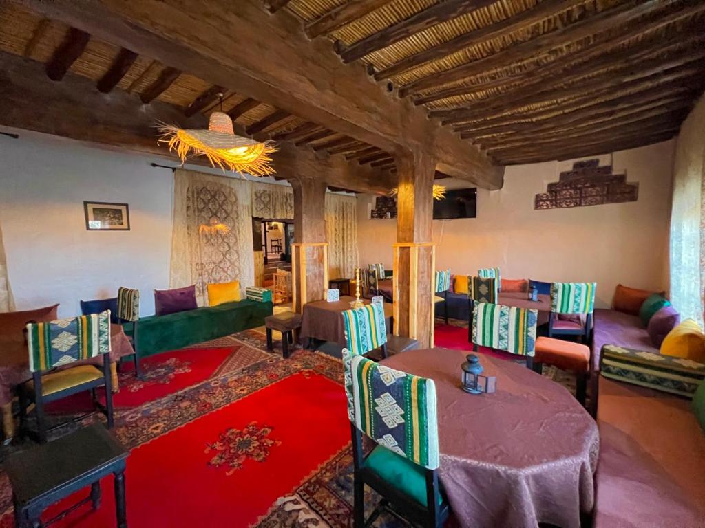 a living room with tables and chairs in a room at Kasbah El Hajja in Aït Benhaddou