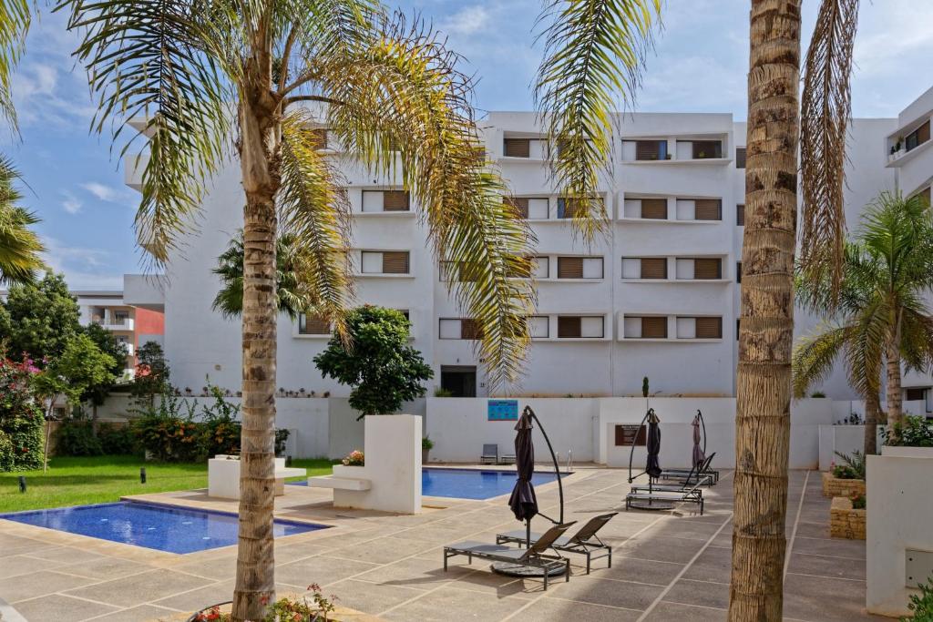 a hotel with palm trees and a swimming pool at Luxury Apartment 90sqm with Pool near Beach WIFI Unlimited Optical Fiber in Agadir