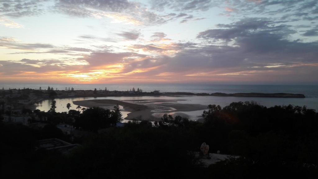 a sunset over a body of water with a city at la Citronnelle in Oualidia