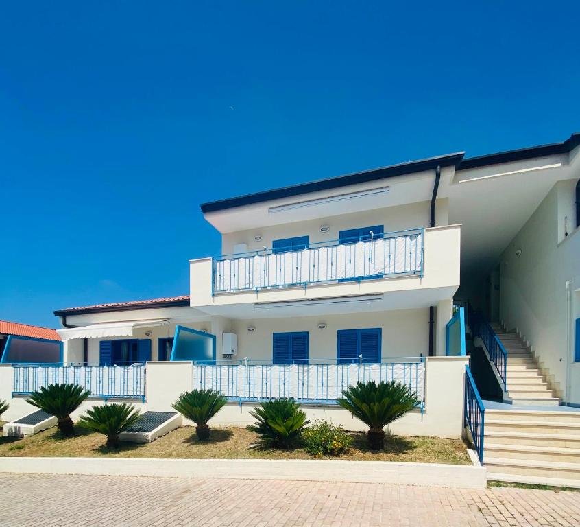 een wit appartementencomplex met een balkon en palmbomen bij Residenza Le Spiagge in Sperlonga