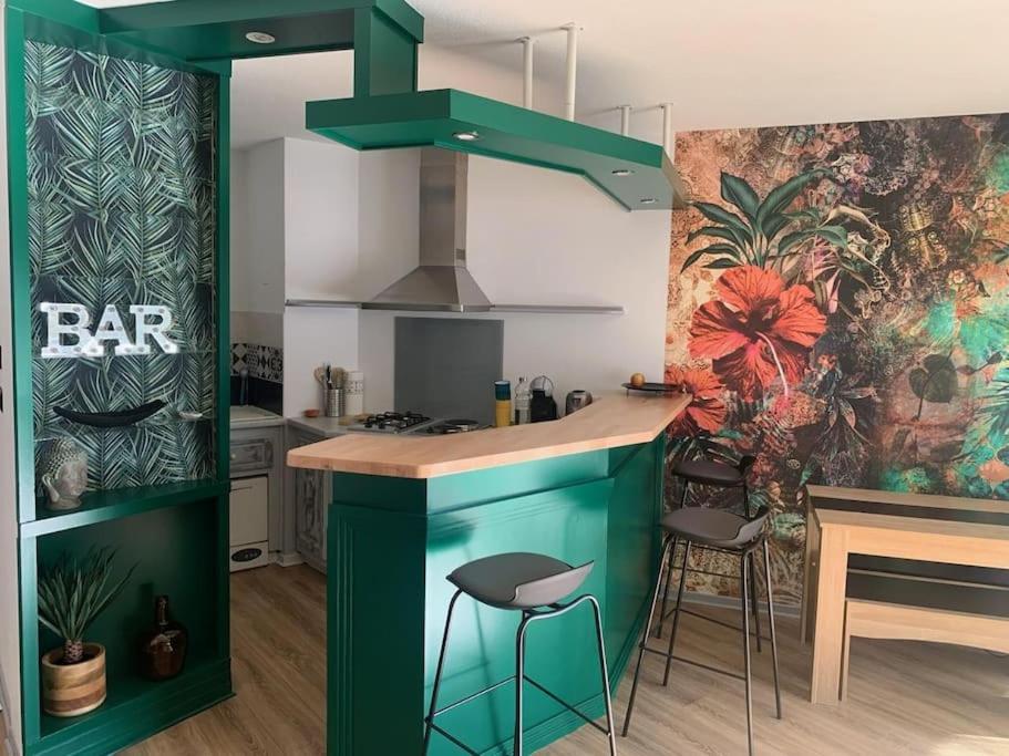 a kitchen with a green island in a kitchen with stools at Cocon douillet résidence calme in Pau