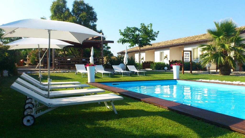 uma piscina com duas espreguiçadeiras e um guarda-sol em Oca Giuliva em Montenero di Bisaccia