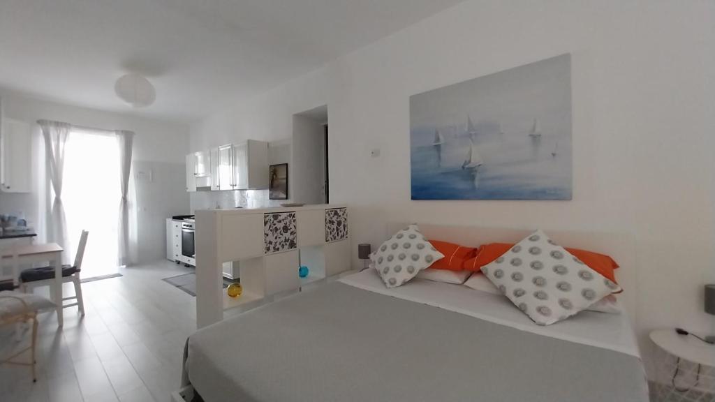 um quarto branco com uma cama e uma cozinha em Casetta Cirantò monolocale em Ischia