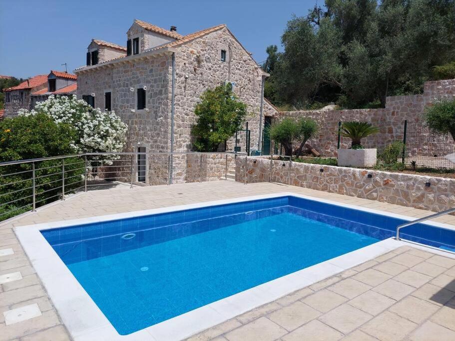 a swimming pool in front of a stone house at Orange Tree House in Šipanska Luka