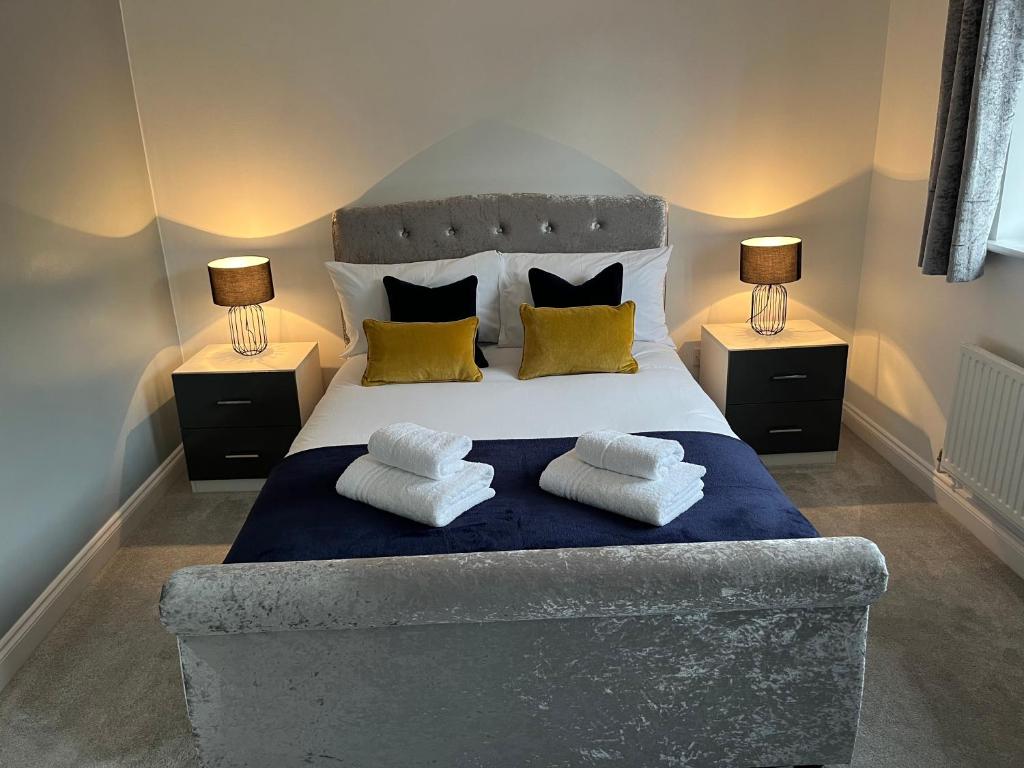 1 dormitorio con 1 cama grande con almohadas y 2 lámparas en The Heathers - Spacious 3 Bed Home From Home, en Burton upon Trent