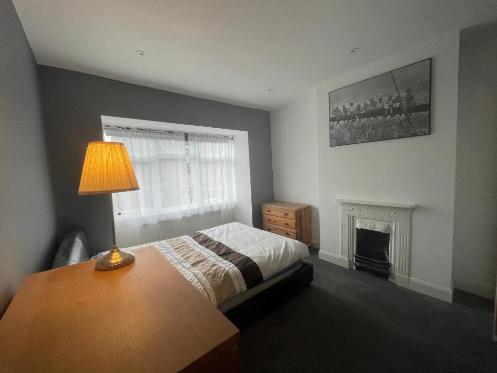 1 dormitorio con cama, lámpara y chimenea en Entire house floor perfect for a couple - available for single too, en Londres