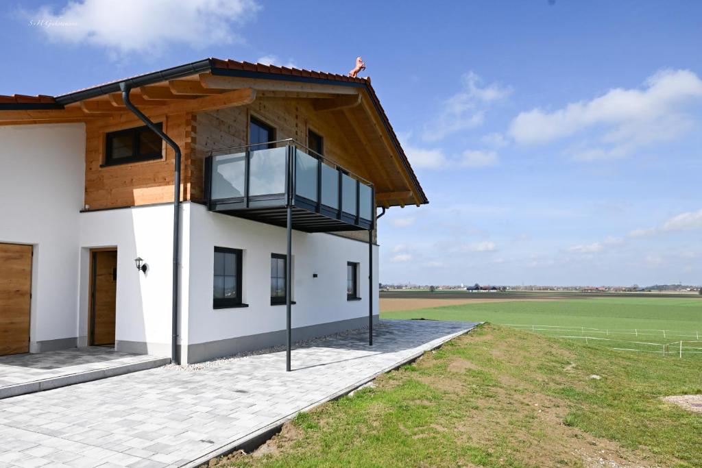 ein Haus mit einem Balkon und einem Feld in der Unterkunft Holzwies Chalets in Unterneukirchen