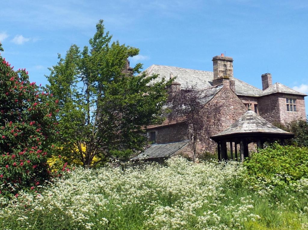 an old stone house with a gazebo in a field of flowers at Johnby Hall in Penrith