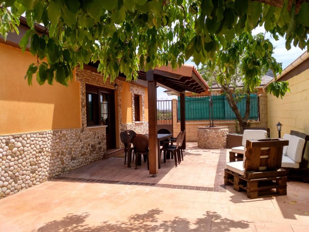 un patio con mesa y sillas y un edificio en La Casita Del Abuelo, en Villalmanzo