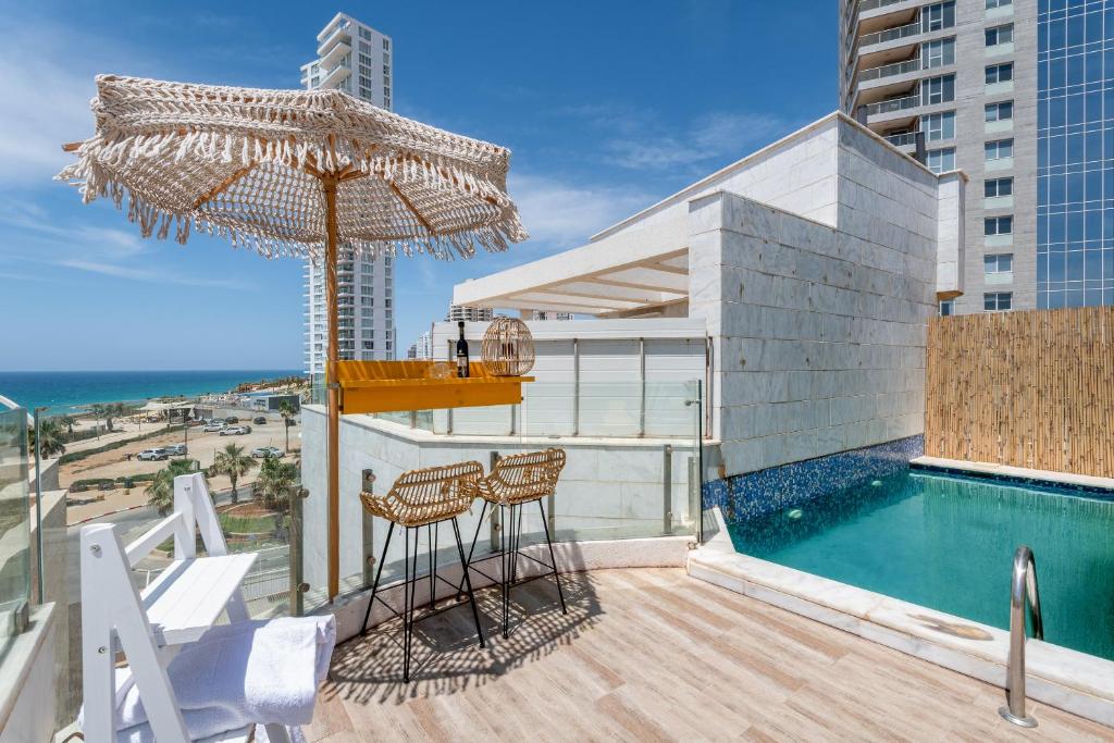 uma varanda com uma piscina e um guarda-sol e cadeiras em Boutique Villa with Rooftop Pool em Netanya