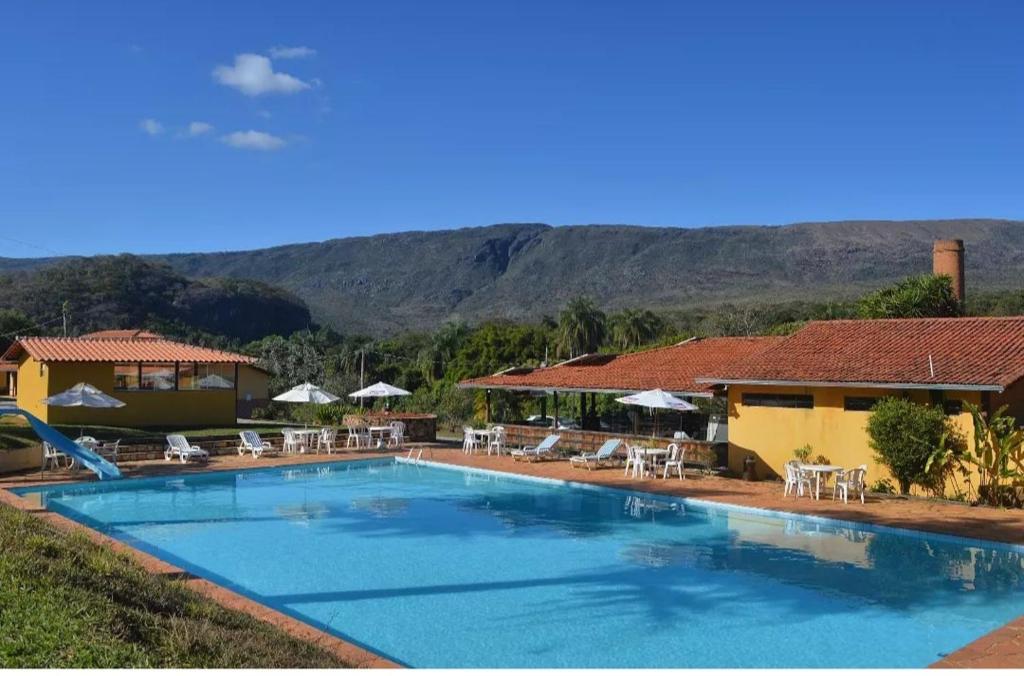 uma piscina com cadeiras e guarda-sóis ao lado de uma casa em Pousada Engenho Velho em Serra do Cipo