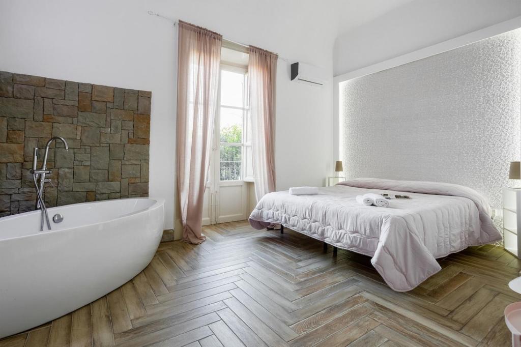 a white bedroom with a bed and a bath tub at Calypso Il Binario Elegance in Palermo