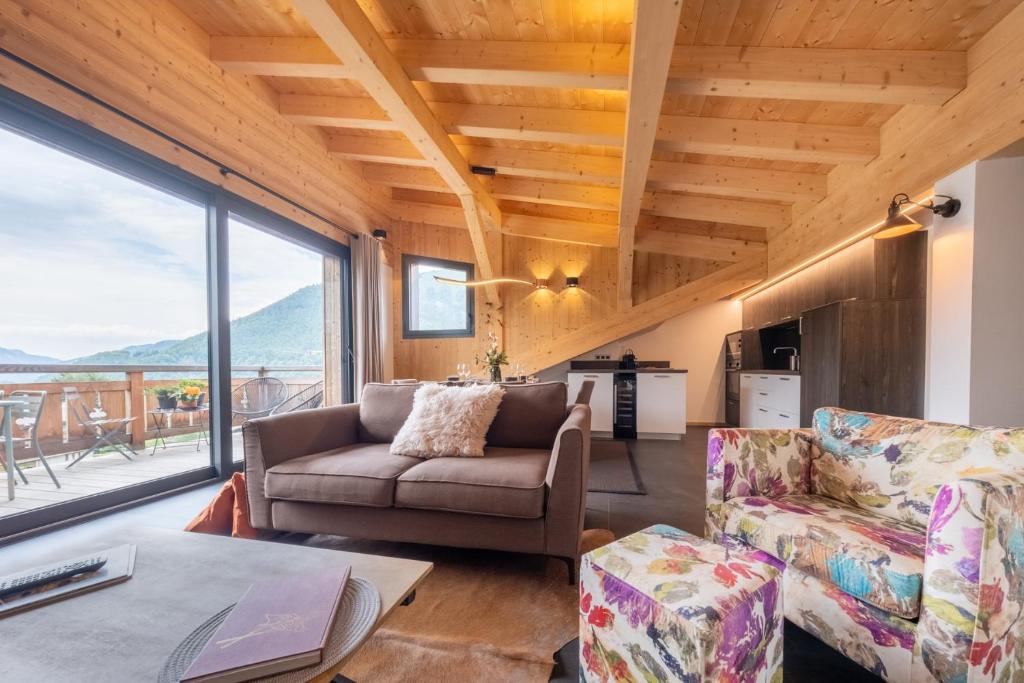 a living room with a couch and chairs and a large window at Appartements Chalet Le Fornay in Morzine