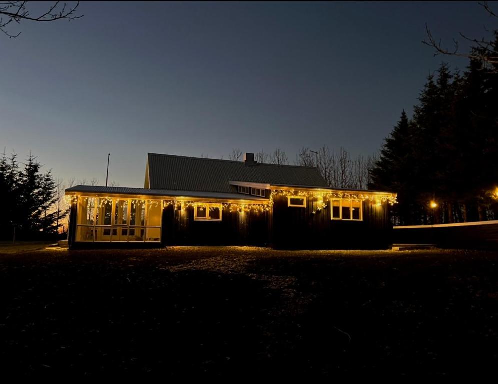 Una casa iluminada por la noche con luces encendidas en Jóhönnu Hús, en Hella