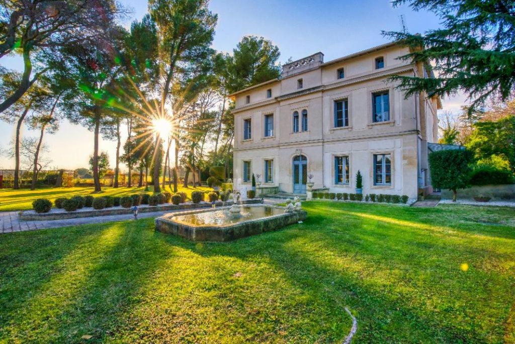 un grand bâtiment blanc avec une fontaine dans la cour dans l'établissement Château Sainte Colombe, à Saint-Geniès-des-Mourgues