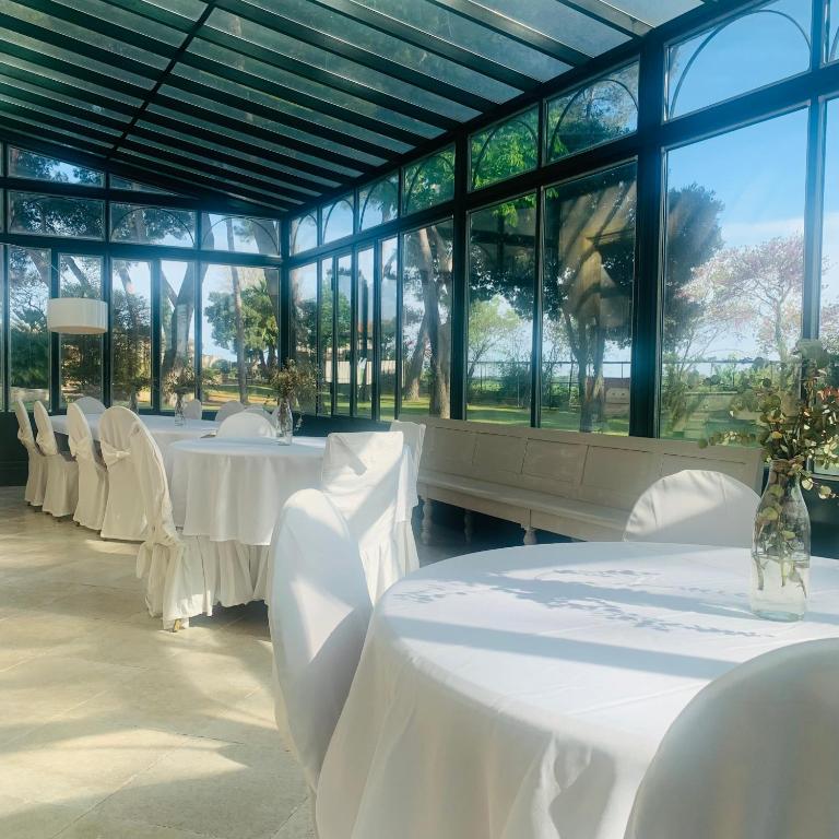 a room with white tables and chairs and windows at Château Sainte Colombe in Saint-Geniès-des-Mourgues