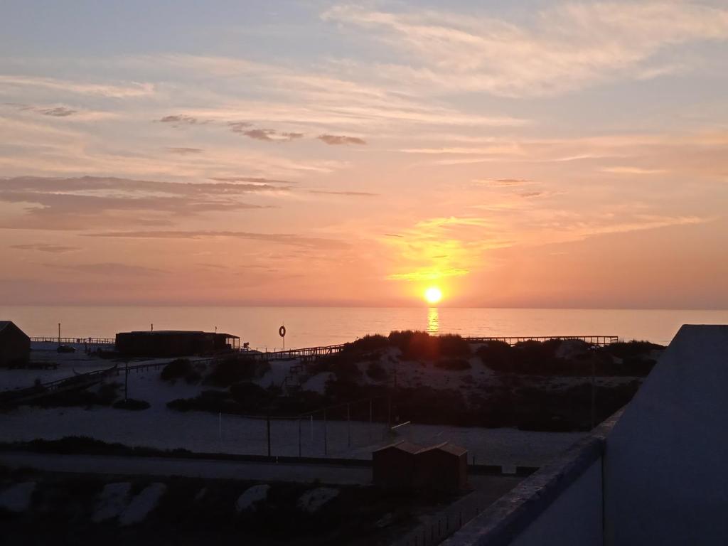 um pôr-do-sol sobre o oceano com o sol no céu em Vagueira Beach Terrace em Praia da Vagueira