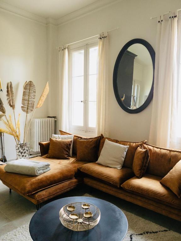 a living room with a brown couch and a mirror at Château Sainte Colombe in Saint-Geniès-des-Mourgues