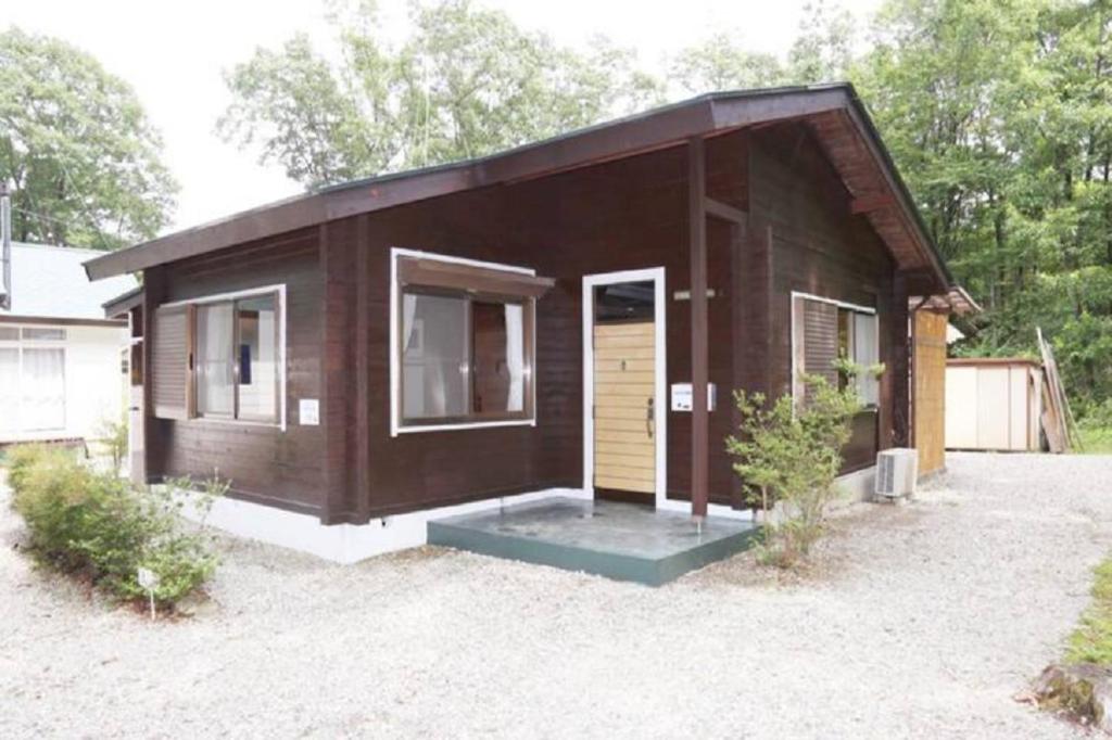una pequeña casa marrón con una puerta en un patio en ウッドペッカー小径 en Nasu
