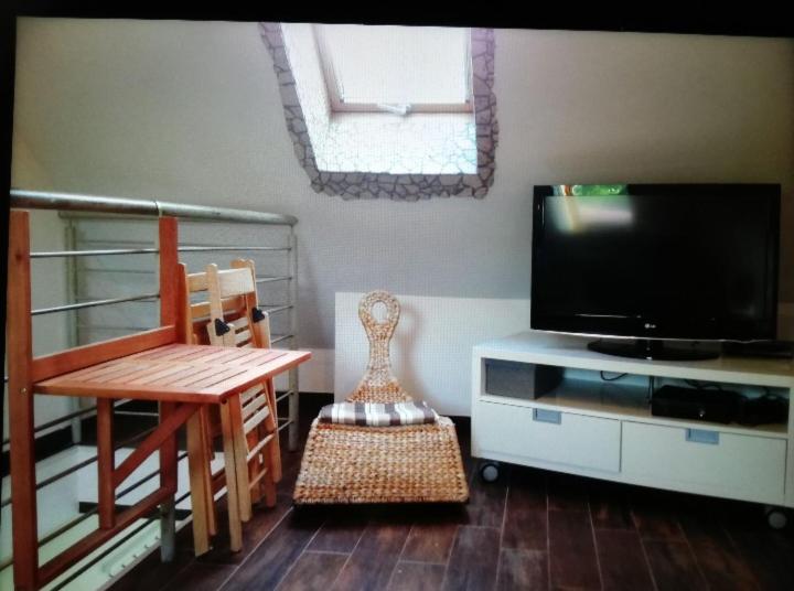 a living room with a flat screen tv and a chair at Schulzis Ferienwohnung in Windeck