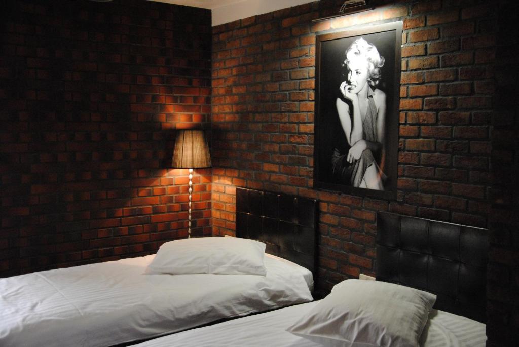 a bedroom with two beds and a brick wall at Amadeus Hotel Zielona Góra in Zielona Góra