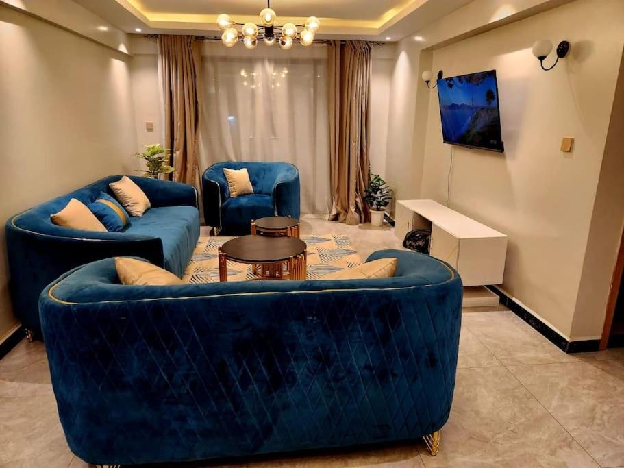 een woonkamer met twee blauwe banken en een tv bij C&C Apartment at Kileleshwa in Nairobi