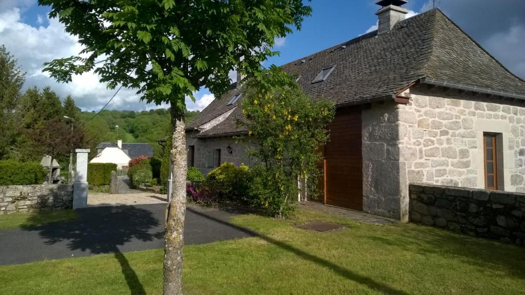 una casa de piedra con un árbol en el patio en Appart'Aubrac, 