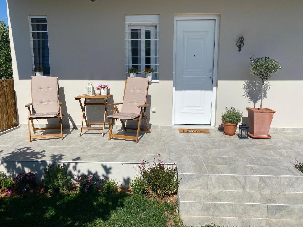 a patio with two chairs and a table and a door at Philia Apartment in Artemida