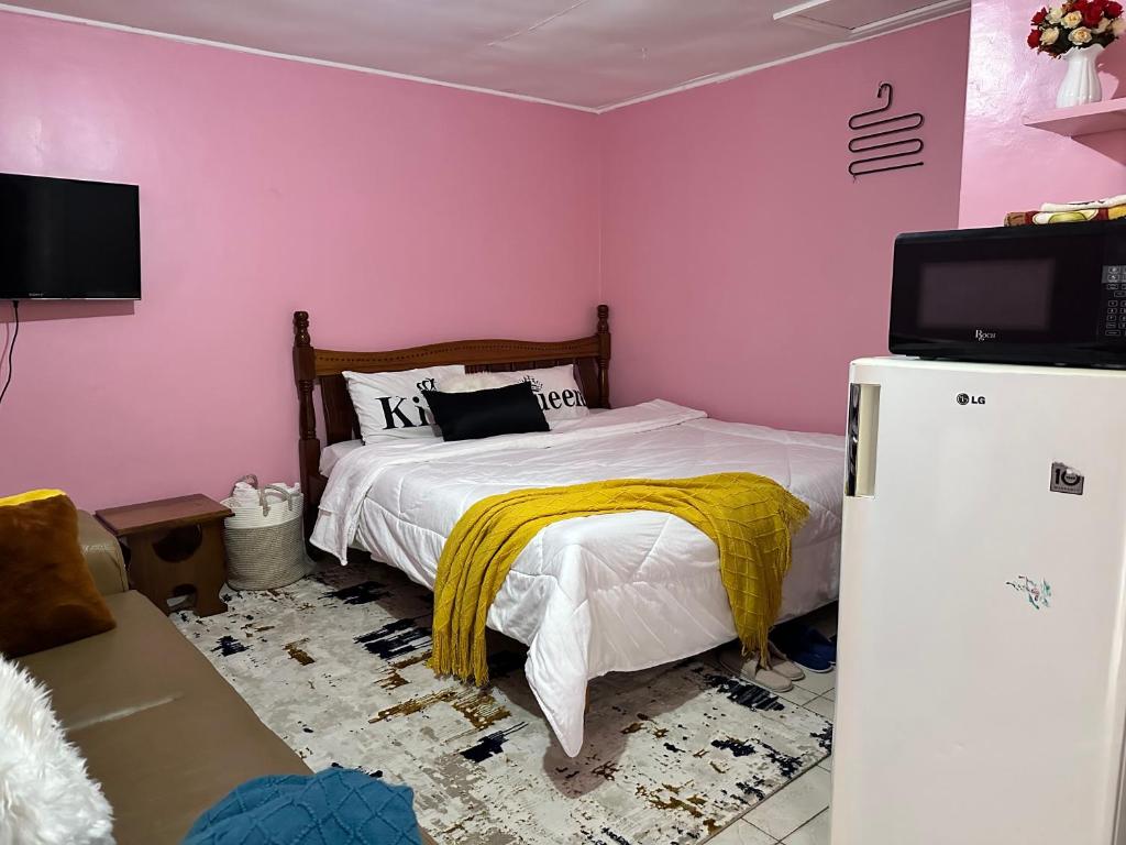 - une chambre avec un lit, une télévision et un réfrigérateur dans l'établissement Ruth's Studio - Kericho, à Kericho