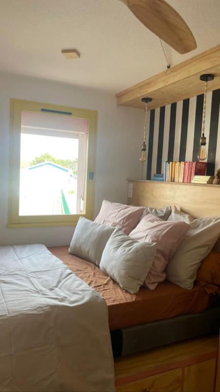 a bed with white pillows and a window in a bedroom at Agréable Loft proche océan classé 1 étoile Refait à neuf in Biscarrosse-Plage
