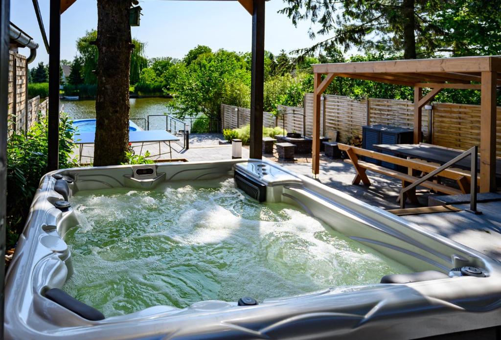 a hot tub in a backyard with a table and a bench at Körös-parti Terasz Vendégház in Békésszentandrás