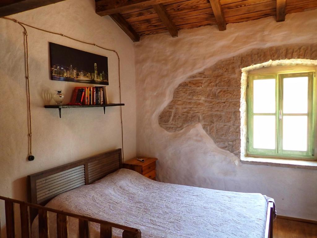 sypialnia z łóżkiem i oknem w obiekcie Cottage al Merlo Olivo w mieście Buje