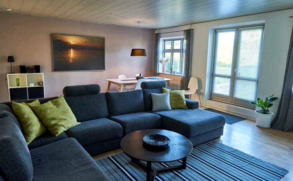 een woonkamer met een blauwe bank en een tafel bij Modern vacation Home - Close to sea and nature. in Hejls