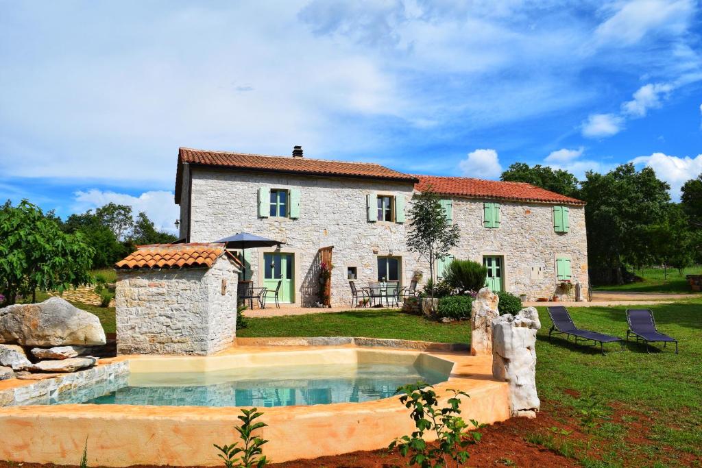 a stone house with a swimming pool in front of it at Cottage al Merlo Olivo in Buje