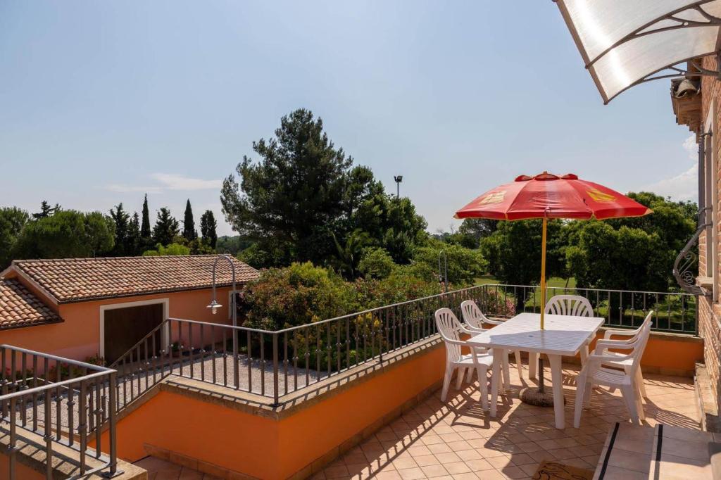 balkon ze stołem, krzesłami i parasolem w obiekcie Villa Martina w mieście Fano