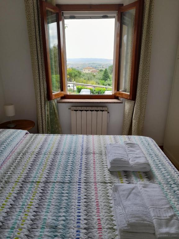 een slaapkamer met een bed met een raam en 2 handdoeken bij Dimora Bellavista in Siena