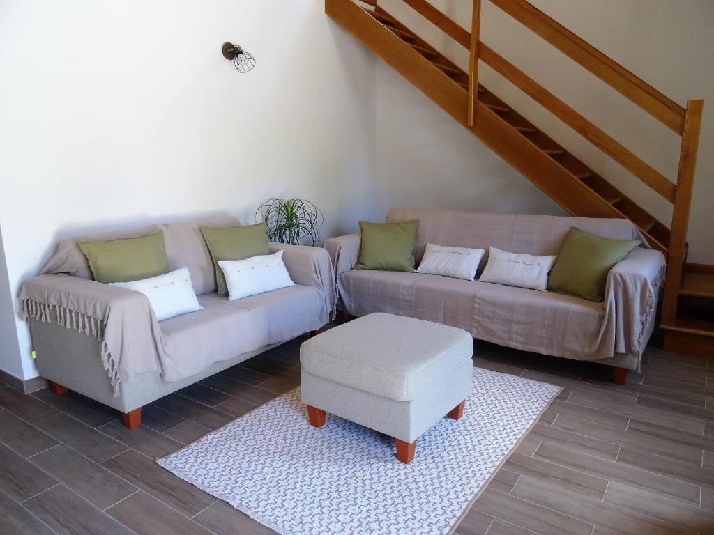 uma sala de estar com dois sofás e um banco em Casa das Andorinhas na Lourinhã