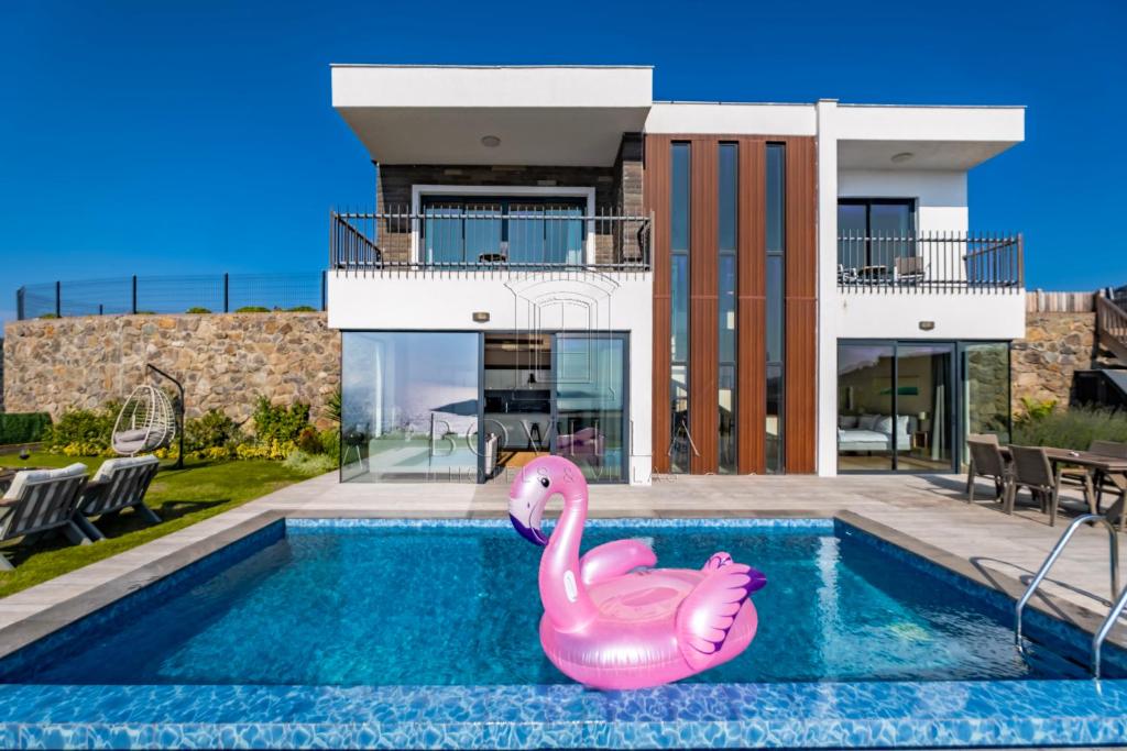 a swimming pool with a pink inflatable flamingo in front of a house at Bovilla Hotel Yalıkavak in Yalıkavak