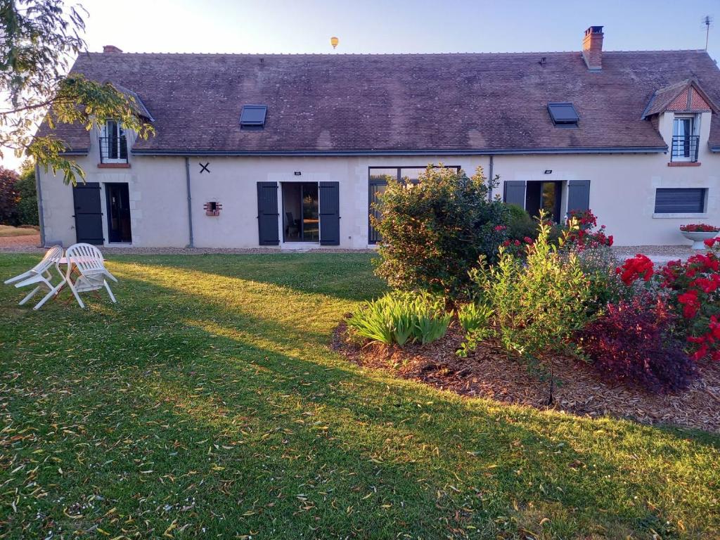 ein weißes Haus mit einem Stuhl im Hof in der Unterkunft Au Ginkgo in Chaumont-sur-Loire