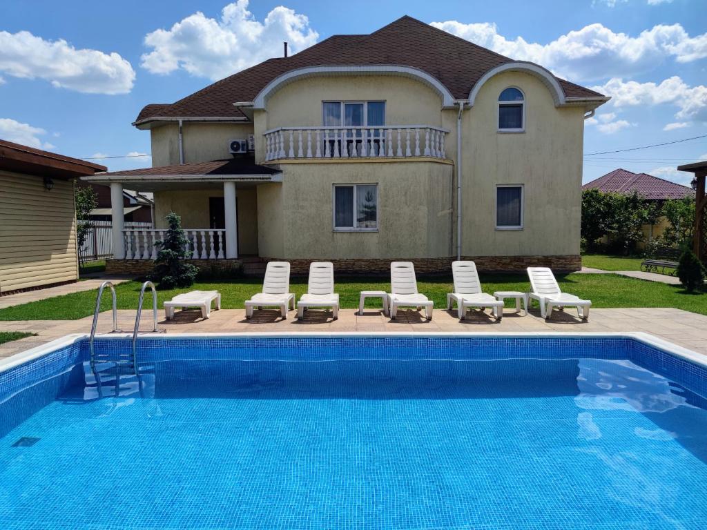 une maison avec une piscine en face d'une maison dans l'établissement Дом с бассейном и сауной, à Boryspil