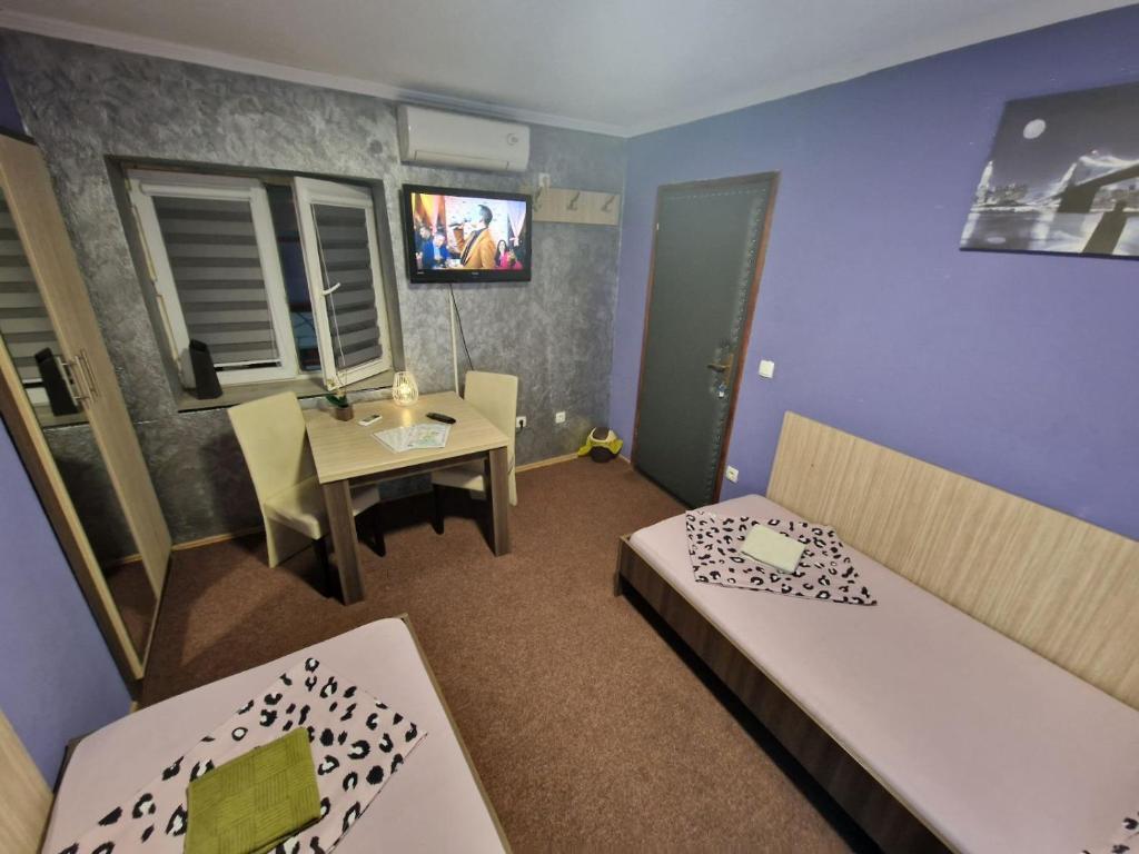 a room with two beds and a table and a tv at Rooms Vedran in Mostar