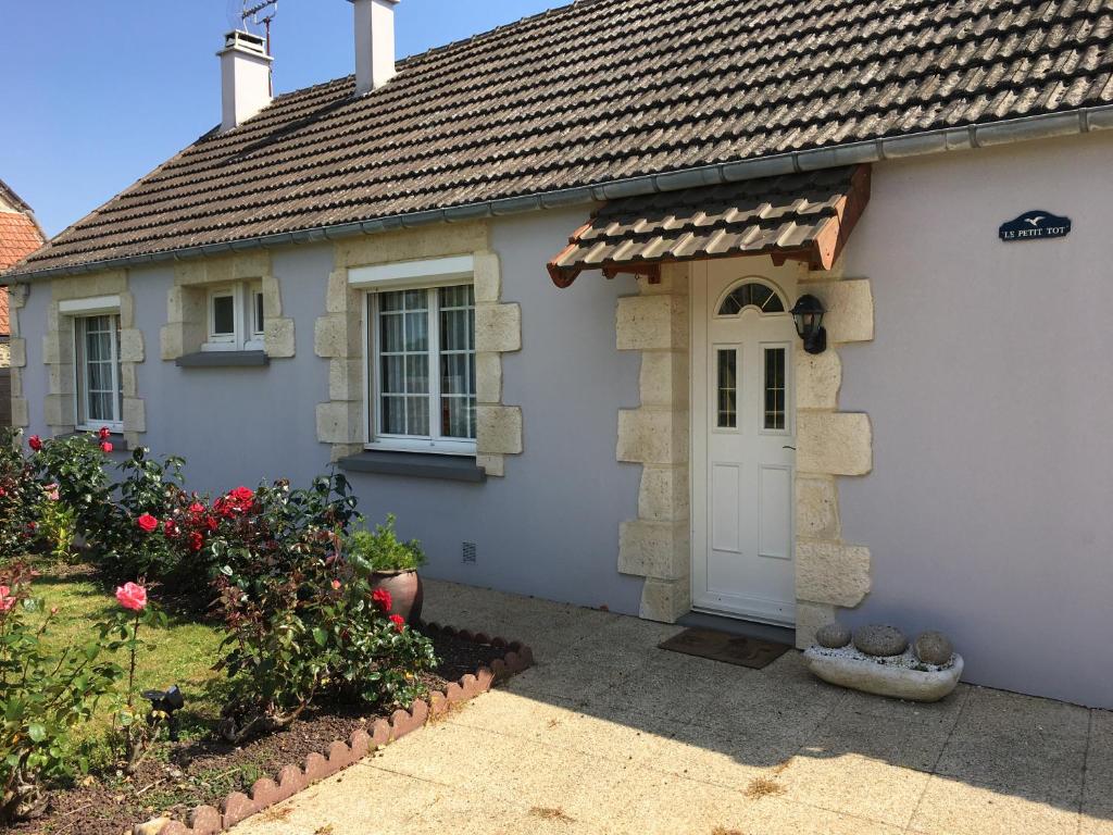 a white house with a white door and flowers at Cottage le petit Tôt in Barneville-Carteret