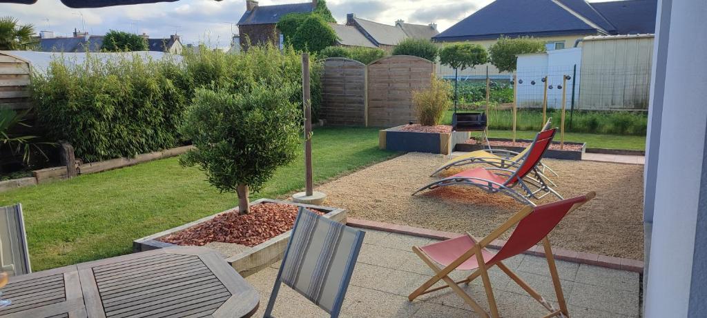 un jardin avec des chaises, un arbre et une aire de jeux dans l'établissement Maison récente avec jardin., à Plourhan