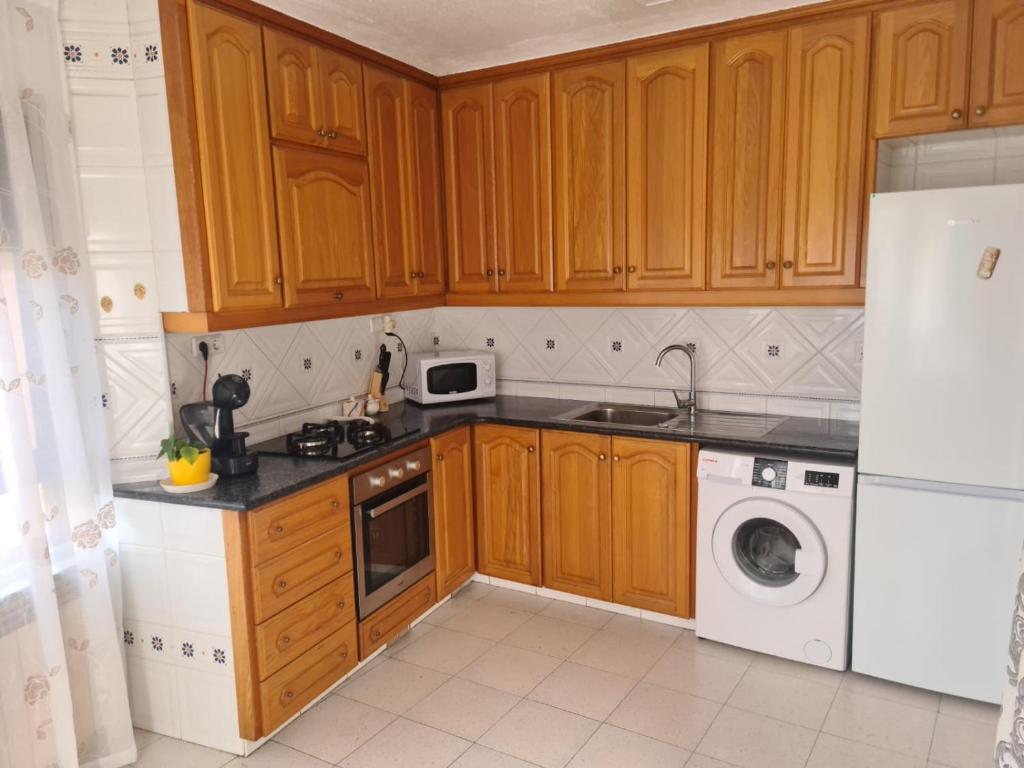 een keuken met houten kasten en een wasmachine en droger bij Allotjament dels Ports in La Senia