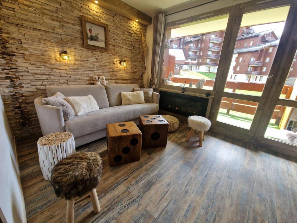een woonkamer met een bank en een bakstenen muur bij Belle-Plagne / Cœur de station / Ski aux pieds in Belle Plagne