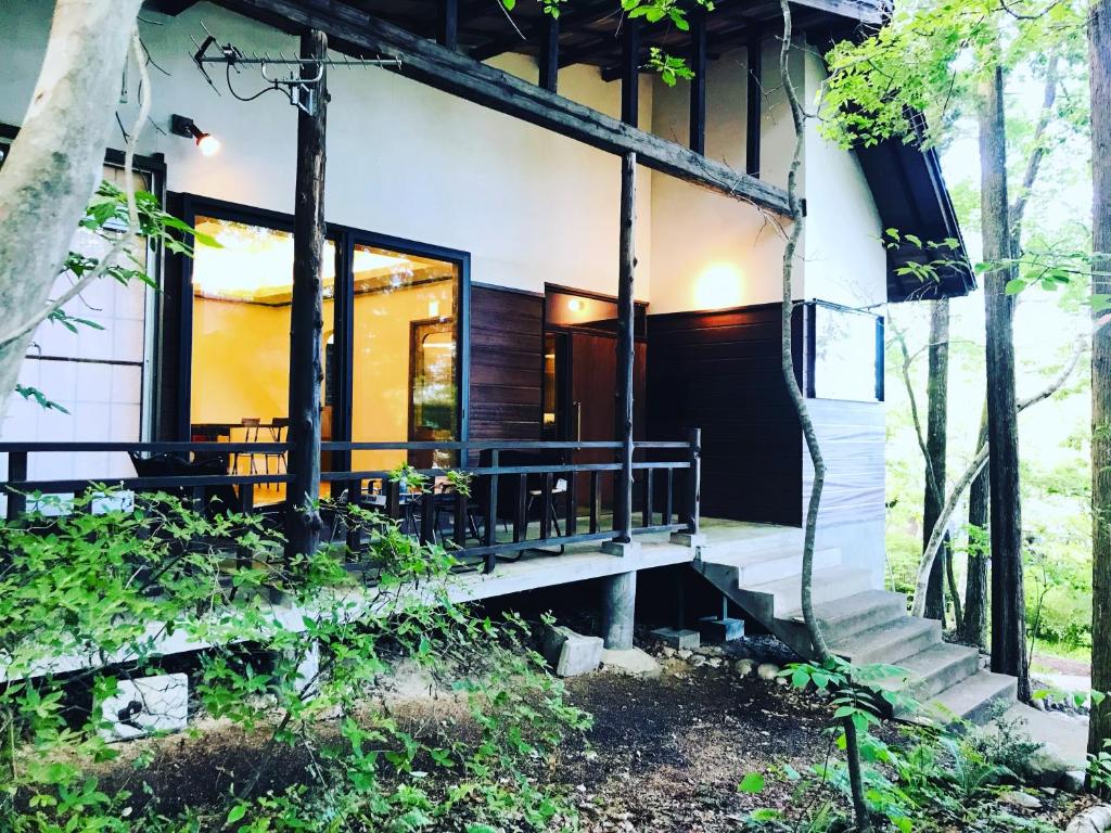 a house in the woods with a porch at 無添加料理と天然温泉つきの ちいさな貸別荘 little villa 柊日 in Azumino