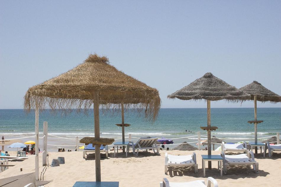 a beach with chairs and umbrellas and the ocean at CC Bay House in Costa da Caparica